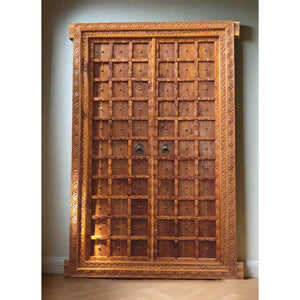 Hand-carved Balinese wooden door with intricate frame and metal accents, luxury home decor