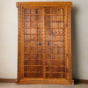 Hand-carved Balinese double wooden door with intricate patterns and metal ring handles
