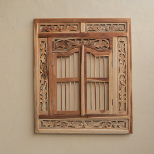 Hand-carved wooden mirror frame with floral Balinese design against a beige wall