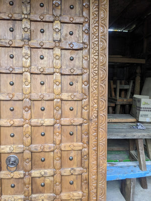 Hand-carved vintage wooden double door with ornate geometric details and iron accents