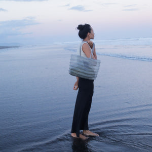 Woman on beach with woven tote bag, coastal style decor inspiration