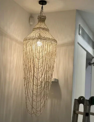 Elegant seashell chandelier with cascading beads hanging in a modern hallway
