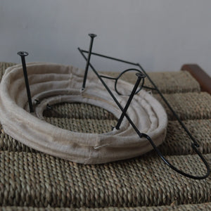 Folded linen table lamp frame with black metal stand on woven surface