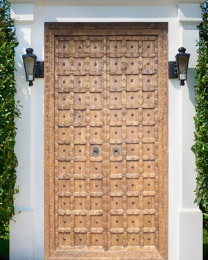 Modern hand-carved wooden door with intricate geometric patterns and ornate frame.