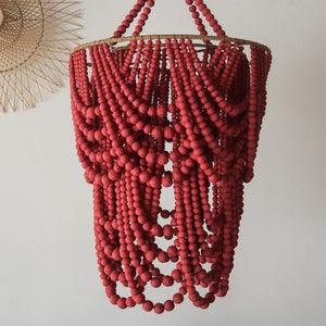Red beaded chandelier with cascading strands, handcrafted hanging decor on white wall