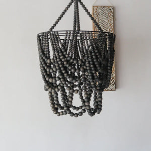 Handmade black beaded chandelier with rustic boho wall art on a white background
