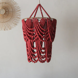 Handmade red beaded chandelier with boho decor on a white wall background