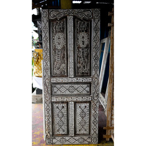 Hand-carved Balinese wooden door with intricate white geometric and floral patterns