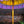 Yellow decorative umbrella with purple tassels against a brick wall