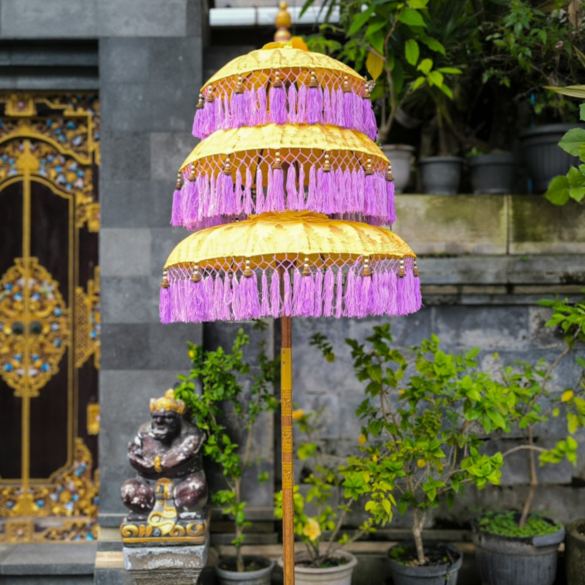 Decorative umbrella with purple canopy in front of a stone building with a decorative door.