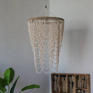 Handmade white seashell chandelier with cascading beads in a minimalist room