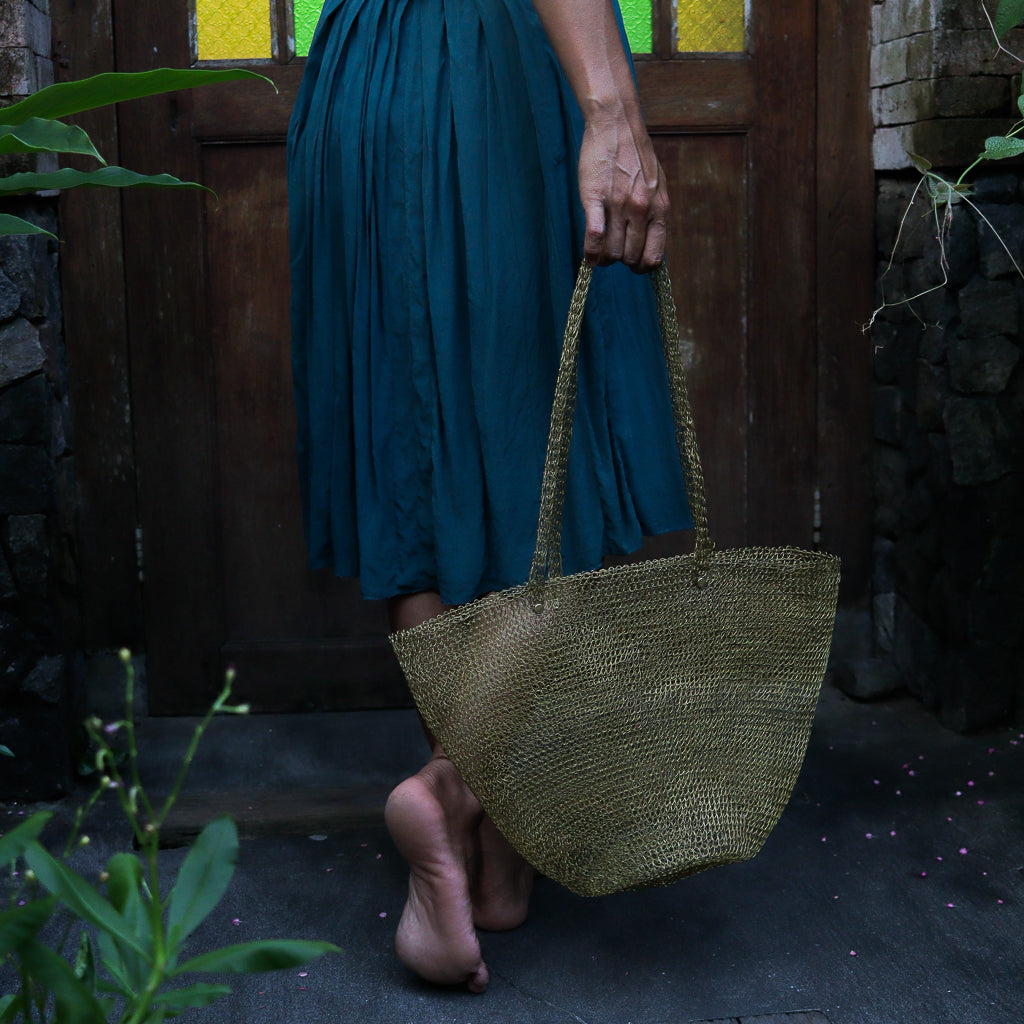 Person holding a woven bag in front of a wooden door
