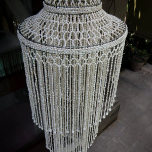 Handmade Balinese seashell chandelier with intricate beaded design, outdoor setting