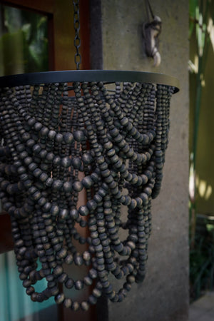 Handmade dark wood beaded chandelier hanging outdoors, artisan Balinese decor