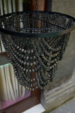 Handmade Balinese beaded chandelier with dark wood beads and black metal frame, outdoor setting