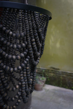 Black wooden bead chandelier with cascading strands in an outdoor setting