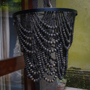 Handmade black wooden bead chandelier with cascading design, hanging outdoors