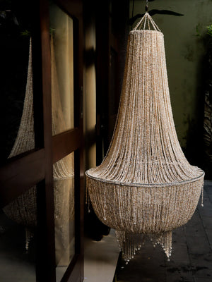 Handmade Balinese seashell chandelier with intricate beadwork hanging outdoors