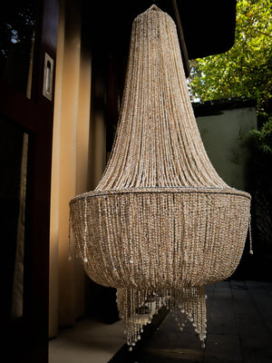 Handmade Balinese seashell chandelier with intricate beaded strands, outdoor setting