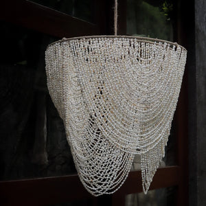 Handmade Balinese seashell chandelier with cascading beaded design, hanging outdoors