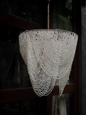 Handmade Balinese seashell chandelier with cascading beaded design, hanging outdoors