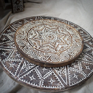 Hand-carved wooden plate with intricate geometric Balinese patterns and rustic finish