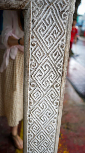 Hand-carved Balinese wood door frame with intricate geometric white patterns