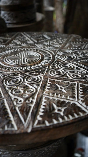 Hand-carved wooden table with intricate Balinese geometric patterns and tribal motifs.