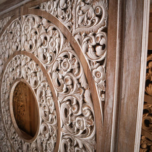 Hand-carved Balinese wood door with intricate floral patterns and circular details