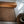 Handwoven natural fiber rug on tile floor beside wooden bed and rustic table in bedroom