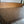Handwoven wooden mat on floor beside wooden bed, eco-friendly home decor accent