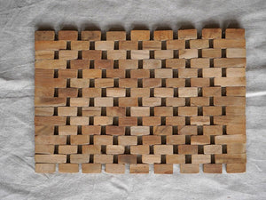 Handcrafted teak wood woven placemat with natural finish on fabric background