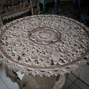 Hand-carved Balinese wood table with intricate floral patterns and distressed finish