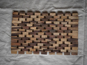 Rectangular hand-carved teak wood mosaic panel with natural brown tones on fabric background