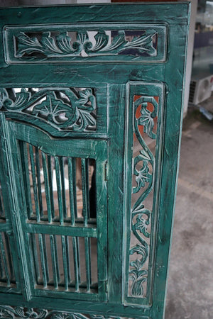 Green hand-carved Balinese wooden door panel with intricate floral patterns