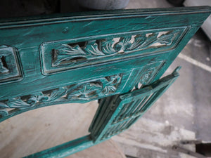 Hand-carved teal Balinese wood door with floral patterns, rustic antique finish.