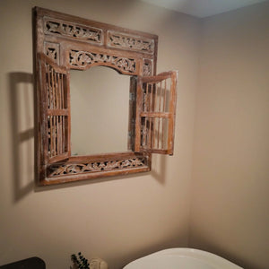 Hand-carved Balinese wood mirror with window shutters in a beige bathroom