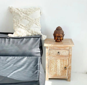 Hand-carved wooden nightstand with a decorative Buddha head and textured white pillow