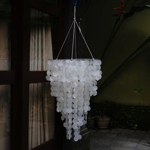 Handmade capiz shell chandelier with round white discs hanging in a shaded outdoor area
