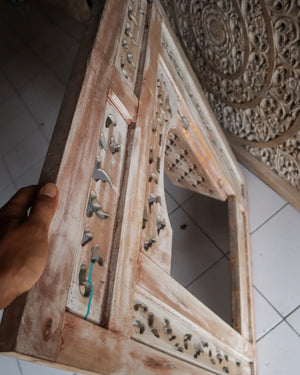 Hand holding carved Balinese wooden frame with intricate vintage floral details