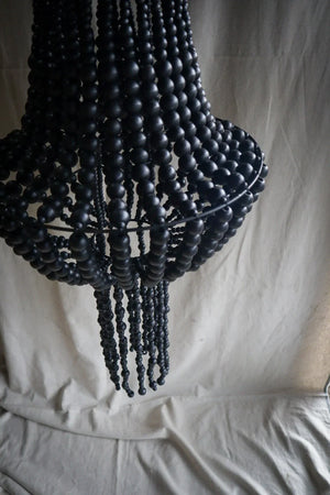 Black beaded chandelier with boho style and unique handcrafted design, hanging indoors.