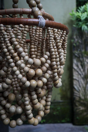 Handmade wooden bead chandelier with natural finish, hanging in an outdoor setting