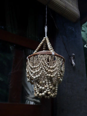 Handmade wooden bead chandelier hanging outdoors, rustic Balinese decor